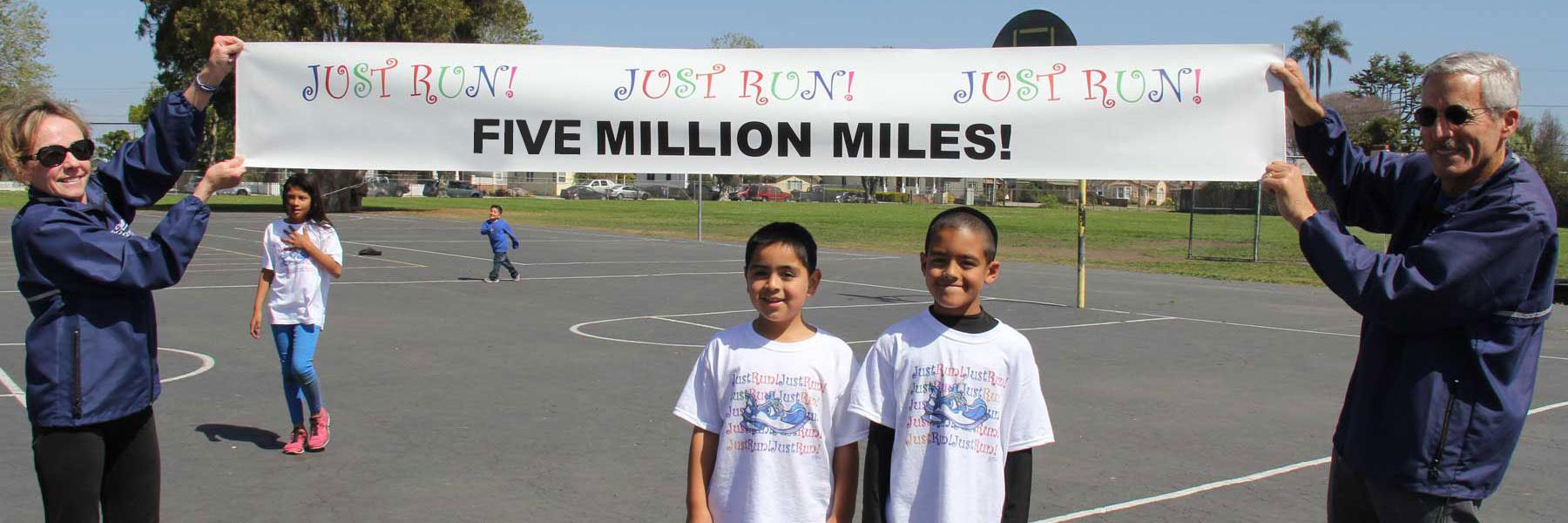 Susan and Mide holding banner with Five Million Miles above two program participants