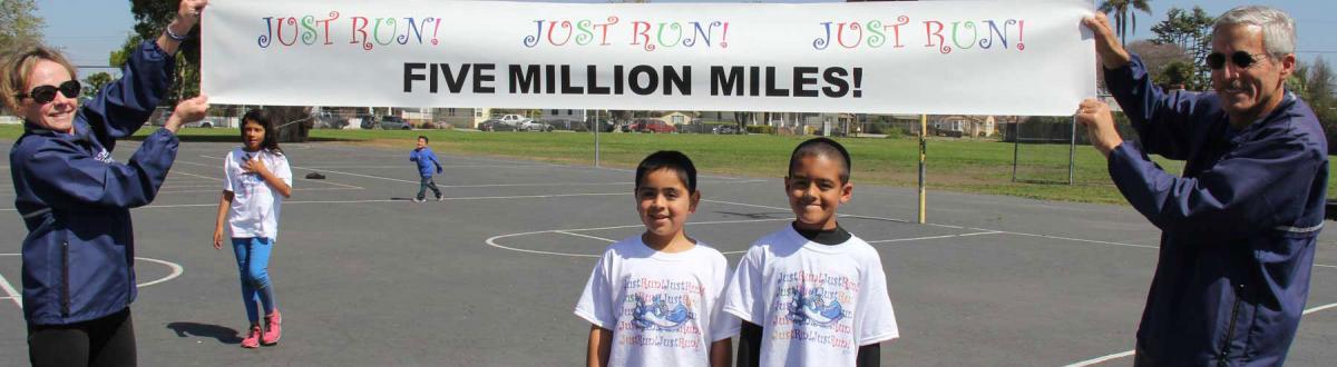 Susan and Mide holding banner with Five Million Miles above two program participants